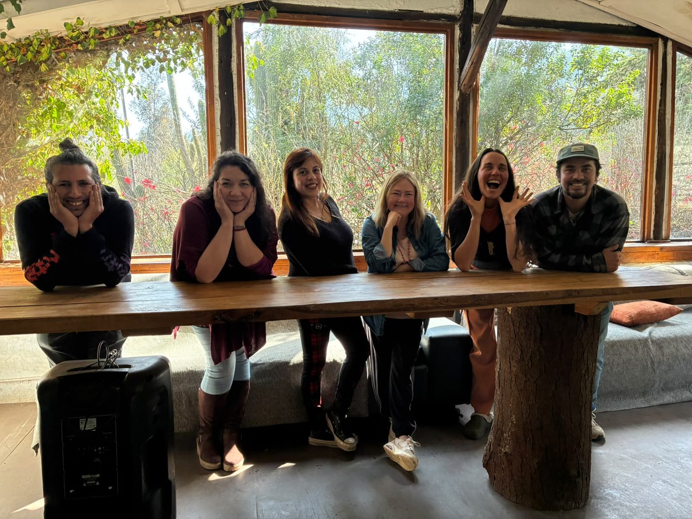 El grupo del primer taller Web con IA posando sonriente en la mesa de madera de Espacio Utopía, con el bosque de fondo