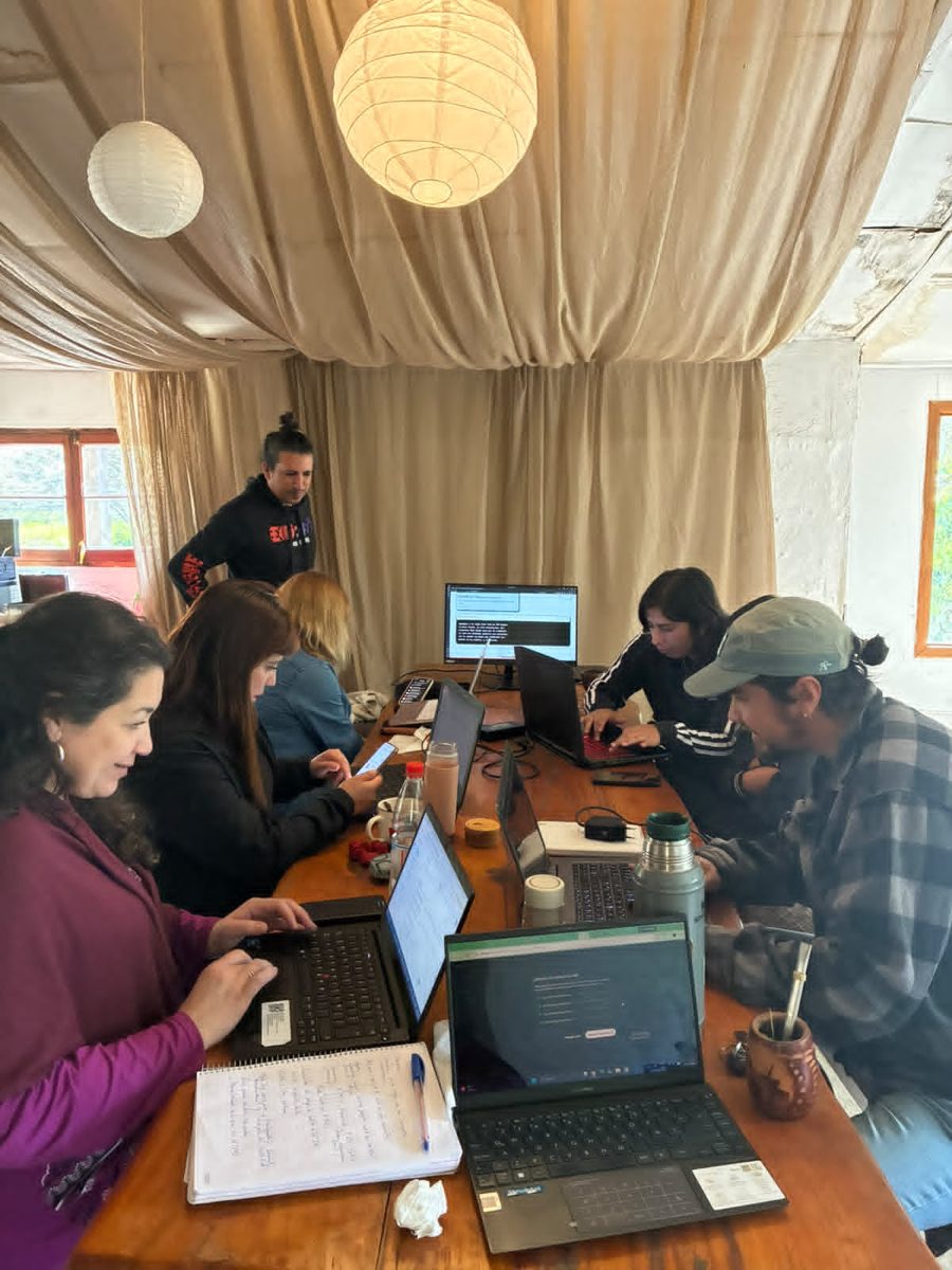 Asistentes del taller trabajando con sus notebooks en una mesa larga, bajo lámparas de papel